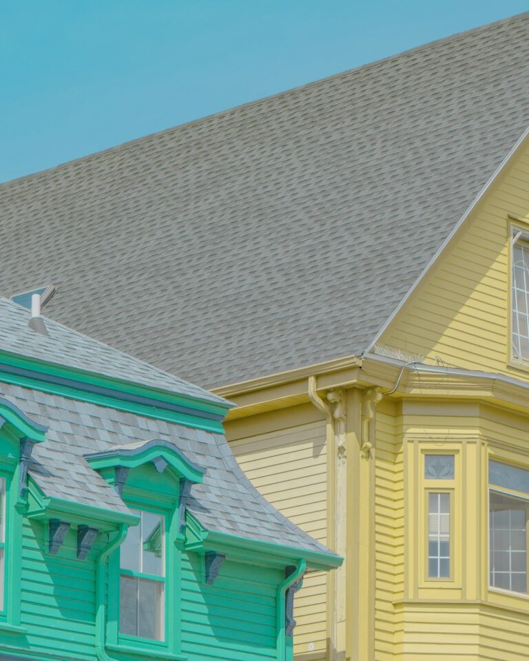 Homeowner compares large roof color samples beside siding and trim on a residential exterior.